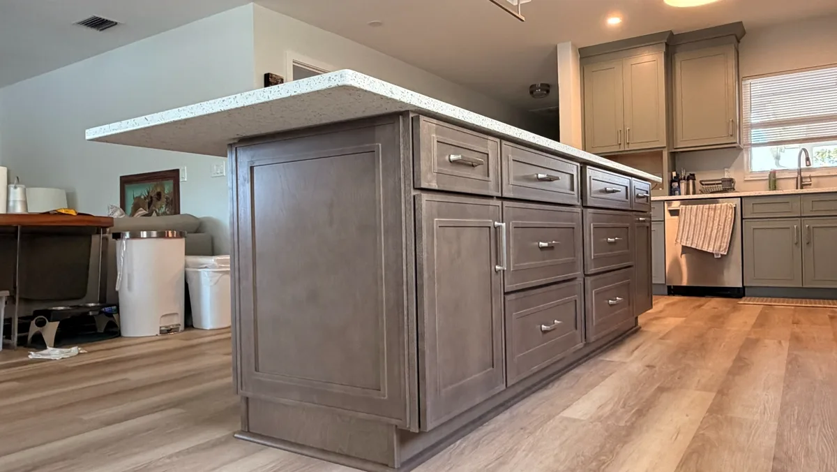 Kitchen with a large taupe island with drawer storage on a wide-plank wood floor