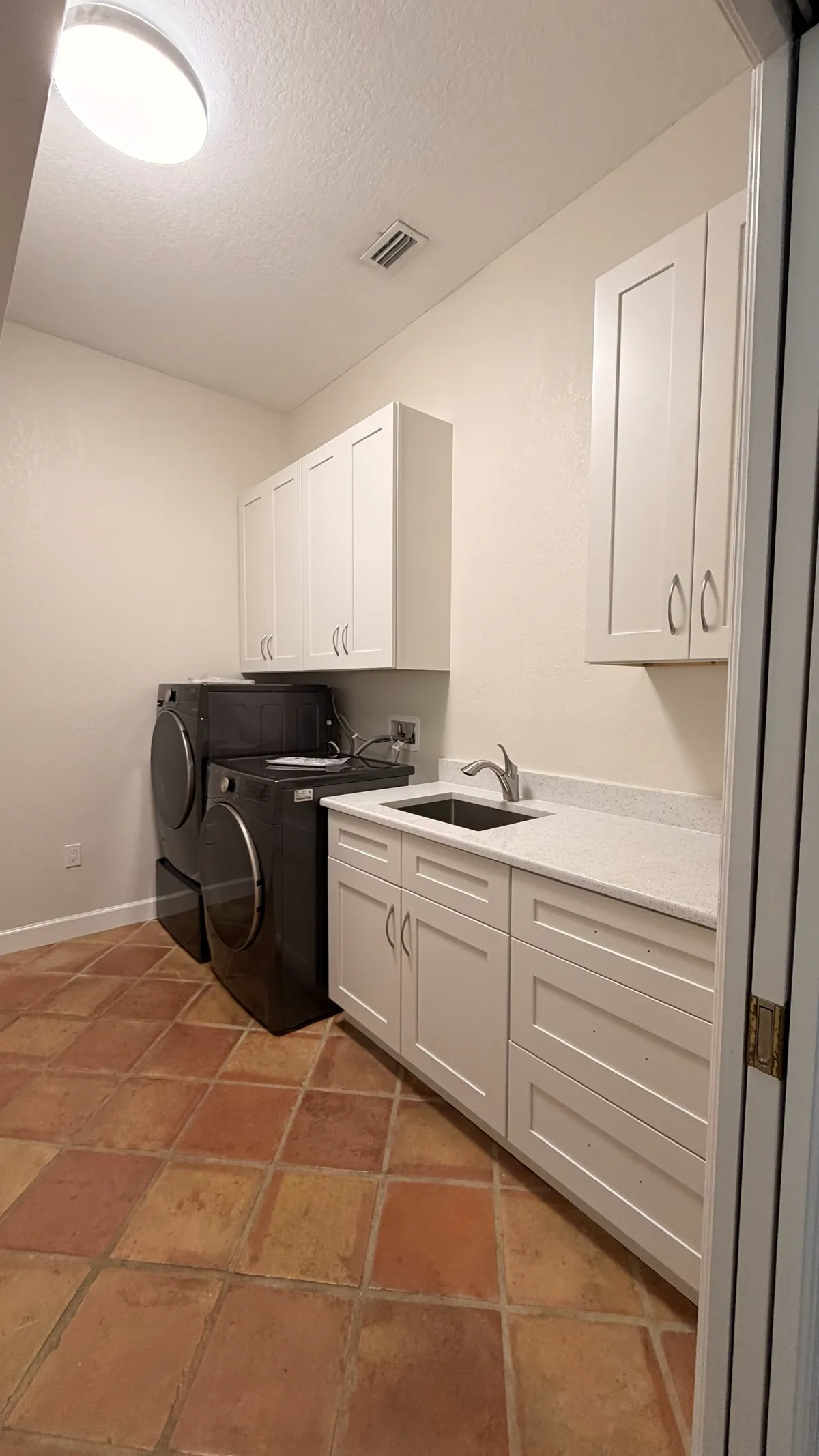 Laundry room by Champion Cabinets with upper cabinets, a quartz worktop and an undermount sink