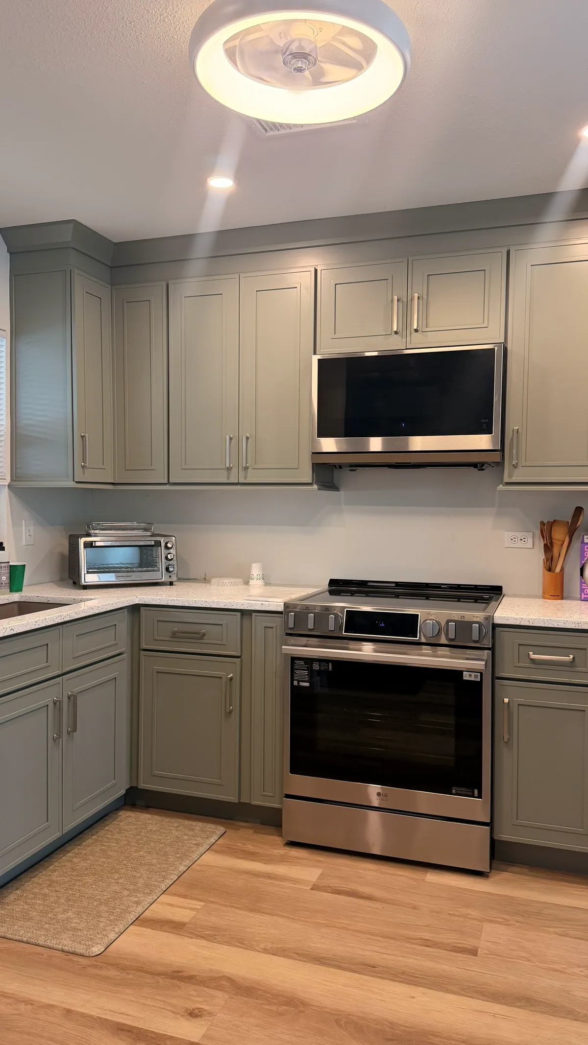 Kitchen with sage green shaker cabinetry, a stainless slide-in range and a marble-look counter