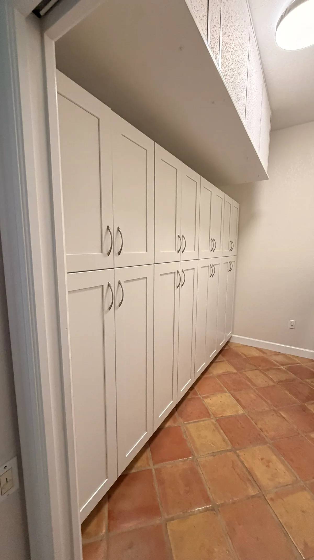 Floor-to-ceiling white storage cabinets filling a recessed alcove, with paired doors at working height and more storage above