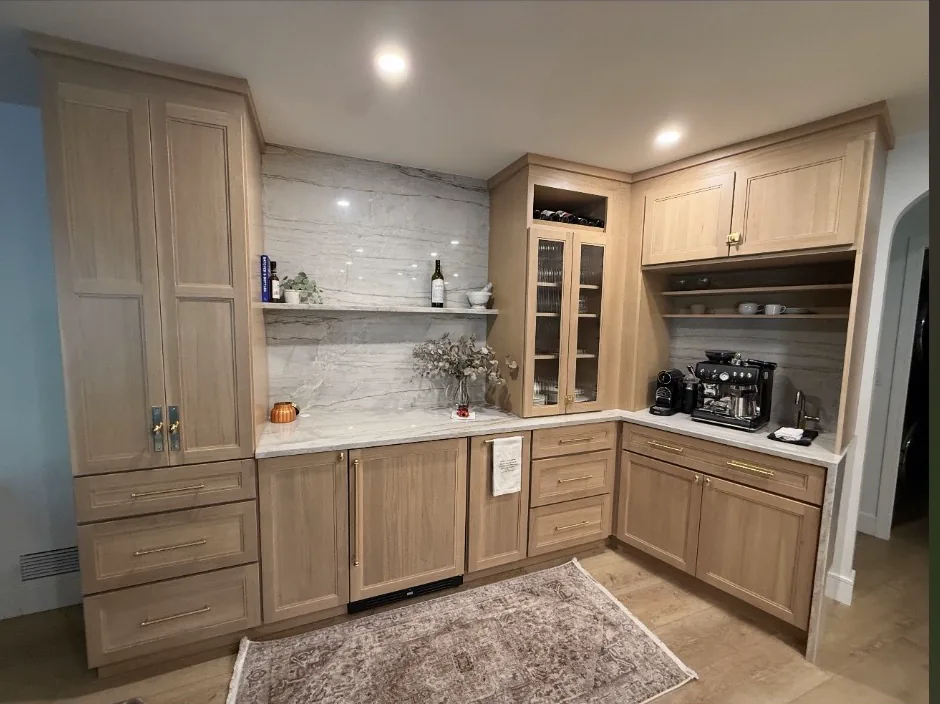 Warm wood cabinetry with a coffee bar, glass-front storage, and brass hardware in a completed Champion project