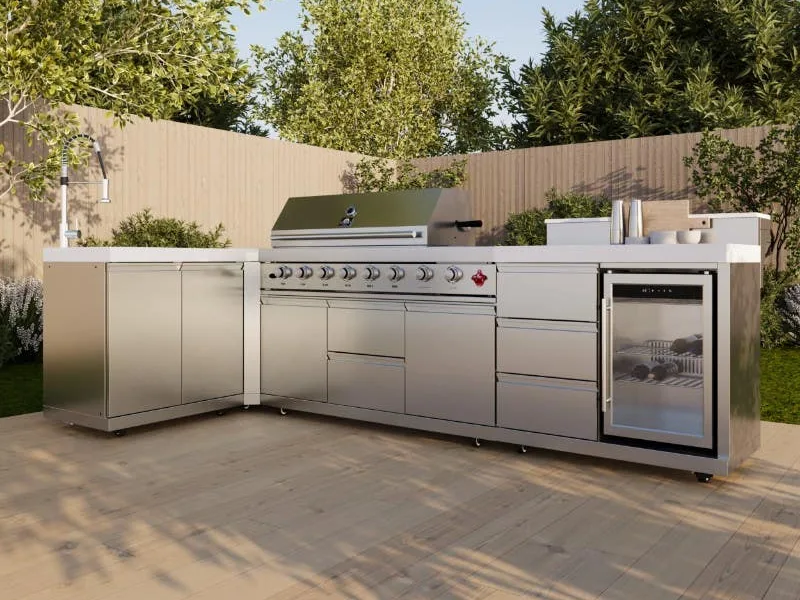 L-shaped stainless outdoor kitchen with light stone counters, a built-in grill, sink and undercounter refrigeration on a timber deck