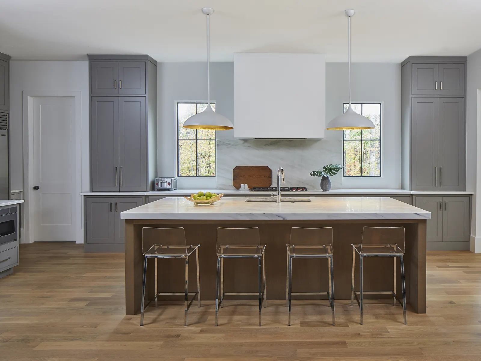 Grey perimeter cabinetry with a wood island and tall windows